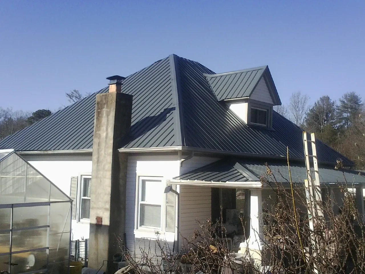 Dark blue standing seam metal roof on a white farmhouse with dormer — Slate & Tile Roof Repair by Roofing Brothers in Lehighton