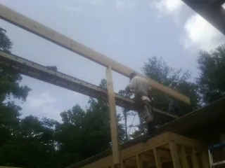 Carpenter setting a ridge beam over a new addition frame in Lehighton
