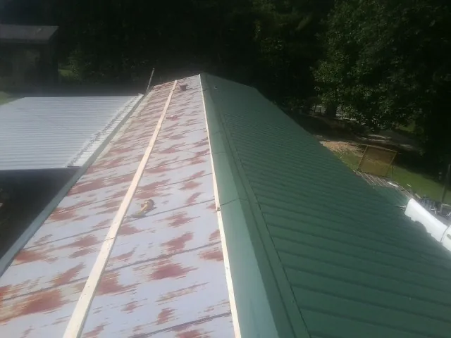 Old rusted panels beside newly installed green metal roofing — Wind Damage Roof Repair by Roofing Brothers in Lehighton