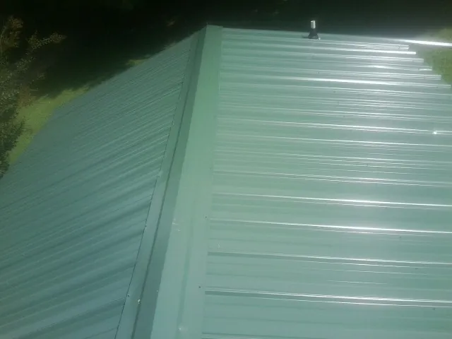 New green metal panels meeting at the ridge of a roof — Flat Roof Repair work by our crew in Lehighton