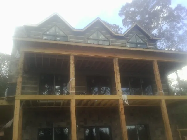 Dormers and porch framing on a large log home under construction — Roof Coating work by our crew in Lehighton