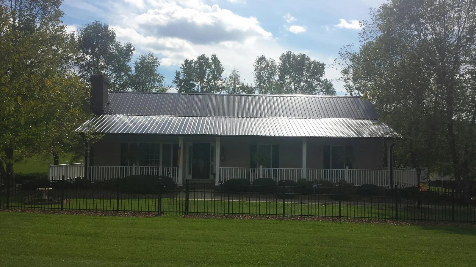 Gray metal roof on a brick ranch with a full width front porch — Gutter Guard Installation work by our crew in Lehighton