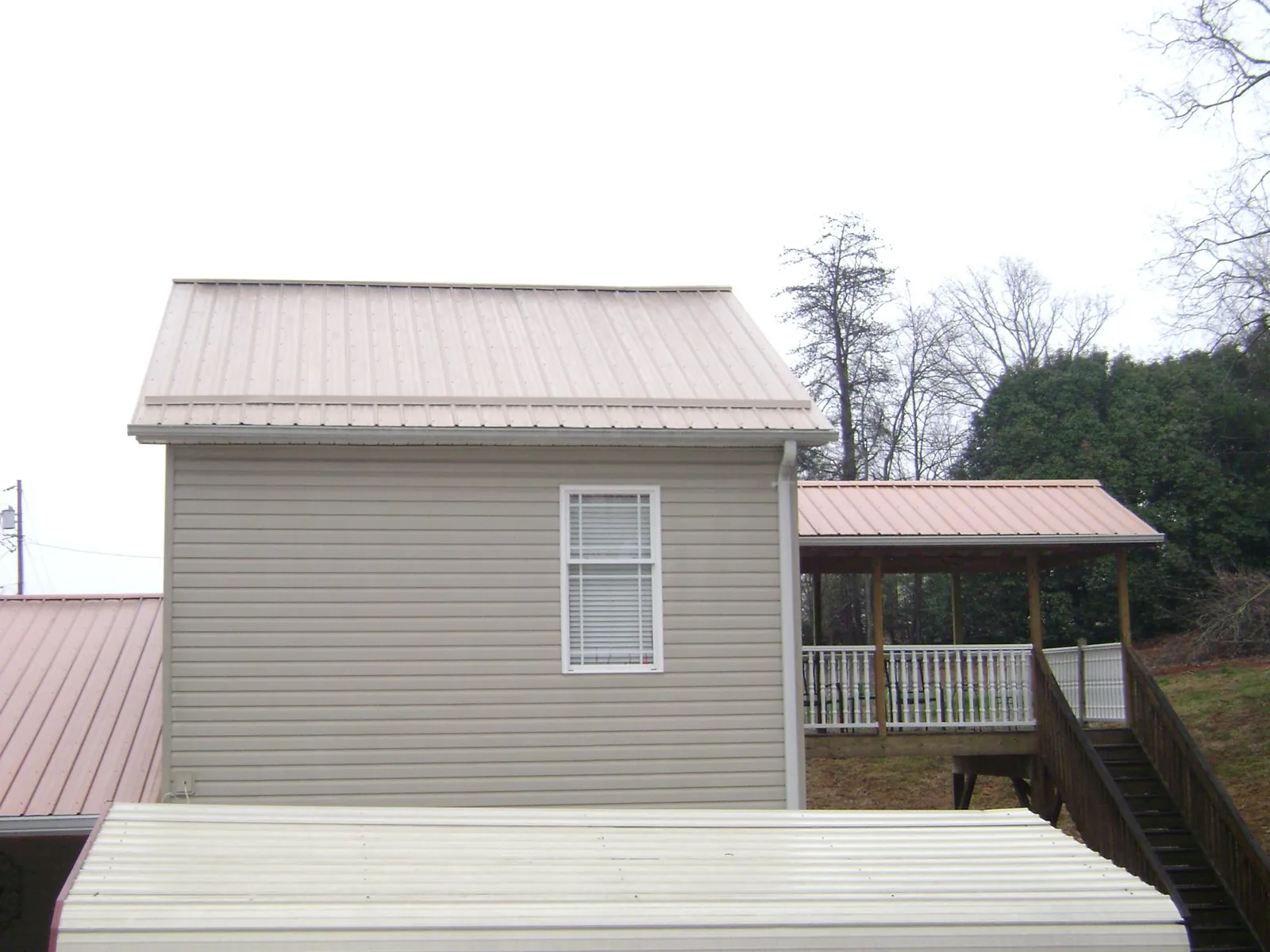 Tan metal roofs on a two story addition and attached porch, from a Roof Replacement job in Lehighton