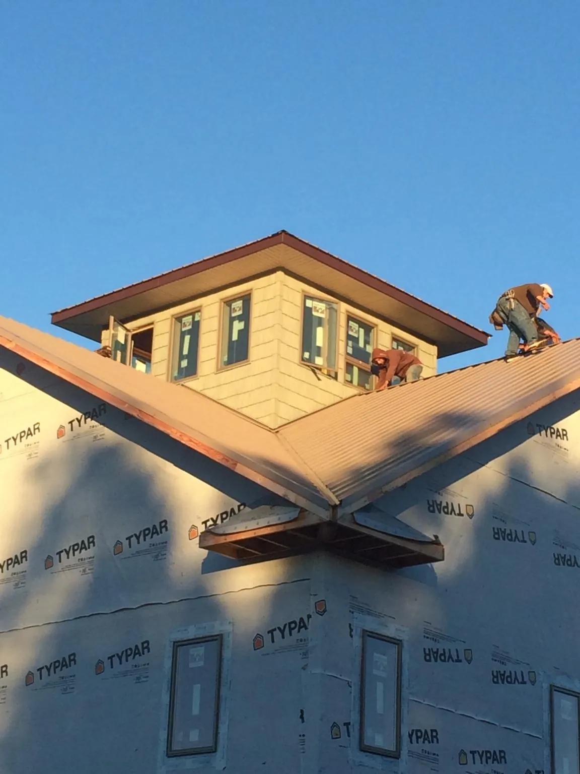 Roofers working around a rooftop cupola on a new metal roof at sunset — Roof Waterproofing in Lehighton by Roofing Brothers
